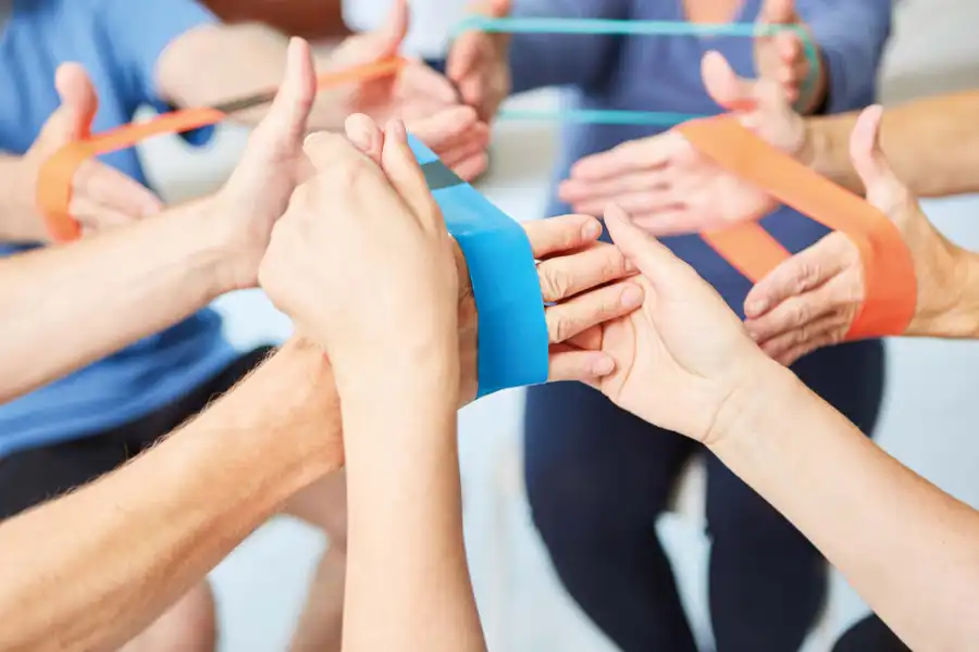 Gruppe trainiert gemeinsam mit bunten Therapiebändern.