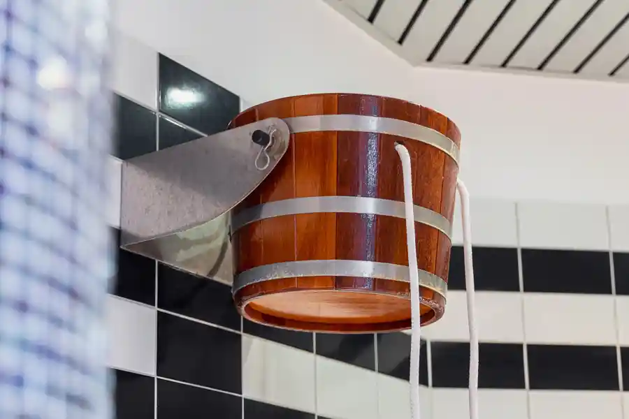 Holzbottich mit Metallbeschlägen an der Wand – Schwalldusche für kalte Güsse nach dem Saunagang.
