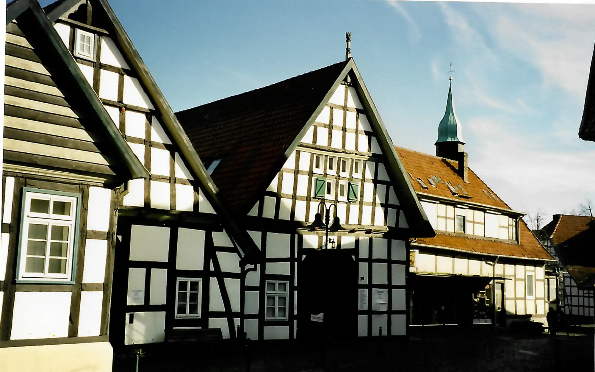 Traditionelles Fachwerkhausensemble mit Kirchturmspitze im Hintergrund.