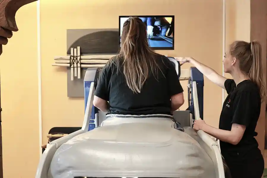 Patientin trainiert im Anti-Schwerkraft-Laufband unter therapeutischer Anleitung.