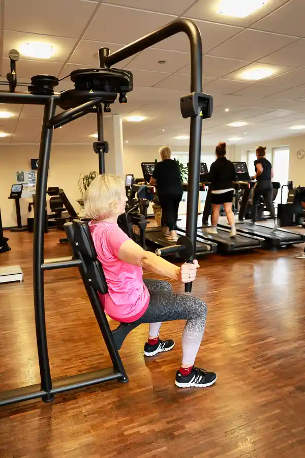 Gerätegestütztes Rückentraining – TechnoGym Biocircuit Frau trainiert an einer modernen Zugmaschine – computergesteuertes Gerät im Biocircuit.