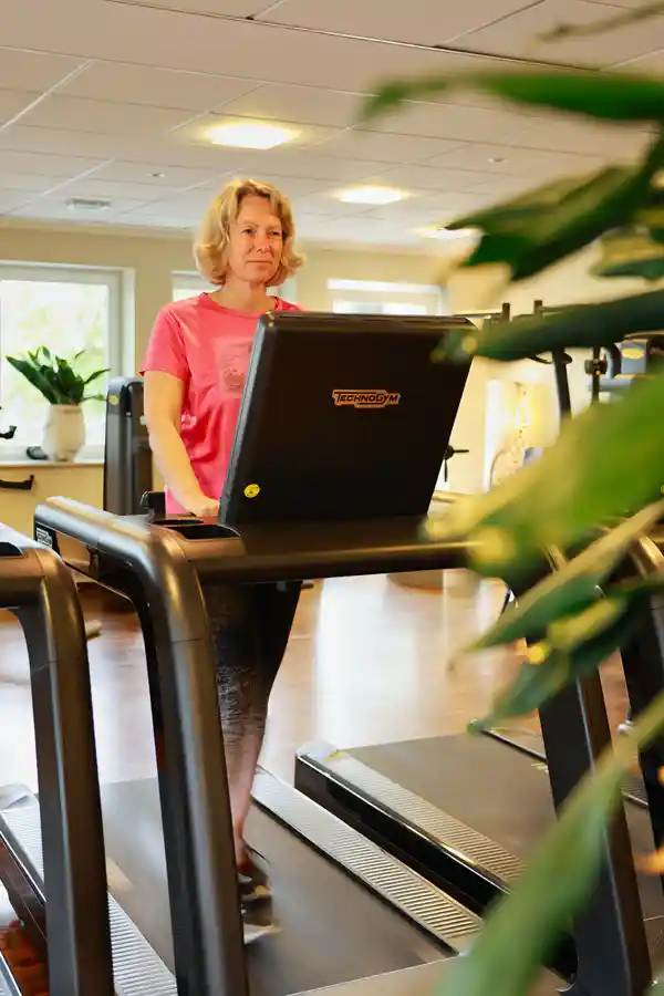 Laufbandtraining TechnoGym Biocircuit Frau geht auf dem Laufband im hellen Trainingsraum – Teil des TechnoGym Biocircuit.