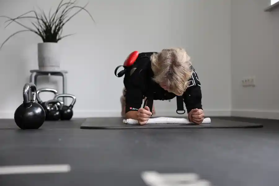 Frau beim EMS-Training in Plank-Position mit Elektrodenweste.