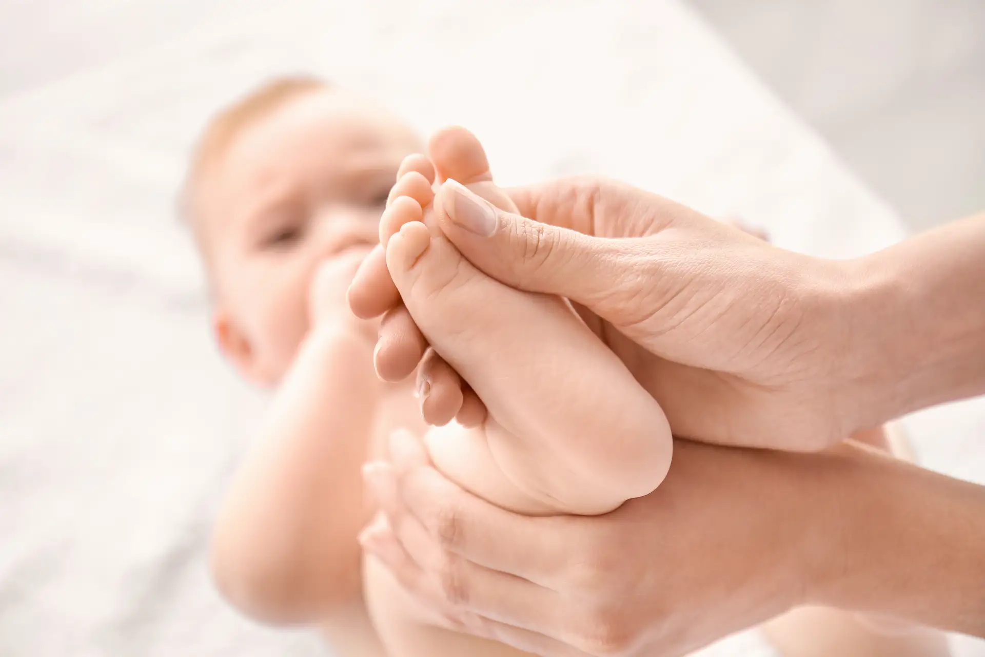 Kinderphysiotherapie – sanfte Behandlung von Babys Therapeutin hält die Füße eines Babys während einer Behandlung – sanfte physiotherapeutische Anwendung im frühkindlichen Bereich.