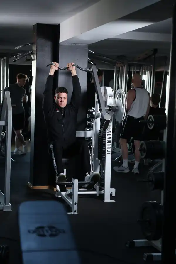 Klimmzugtraining im AKTIVITA B.E. GYM Mann führt Klimmzüge an einer Trainingsstation aus.